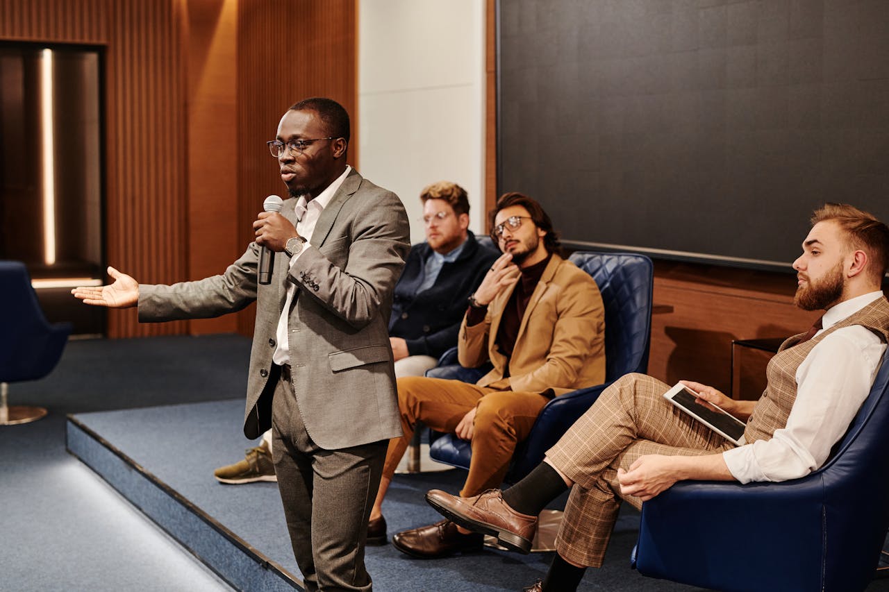 A business professional presenting at a conference with a diverse and attentive audience.